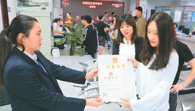 河北省承德市網(wǎng)絡(luò)代購經(jīng)營者陳晨(右)從工作人員手中接過帶有統(tǒng)一社會信用代碼的營業(yè)執(zhí)照。 劉環(huán)宇攝(人民圖片)