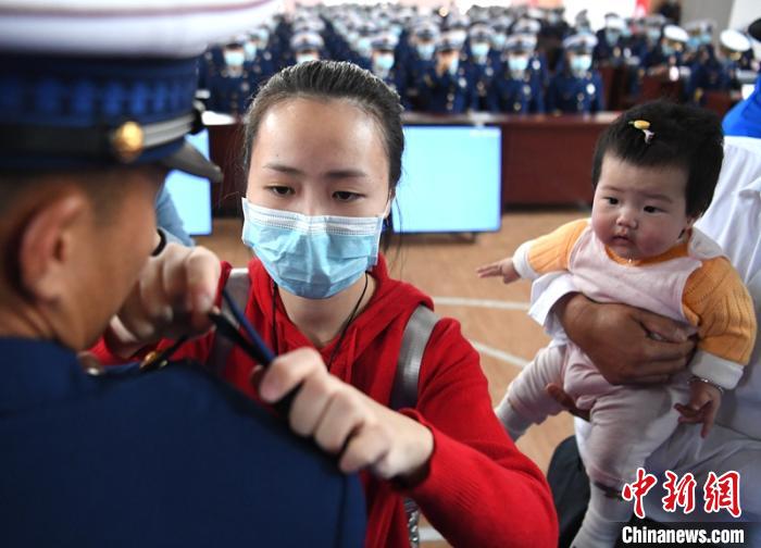 新消防員楊振的妻子彭莉與女兒現(xiàn)場見證丈夫加入“火焰藍”的神圣時刻?！⒅铱?攝